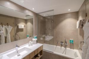 a bathroom with a tub and a sink and a mirror at Hôtel La Villa Douce in Rayol-Canadel-sur-Mer