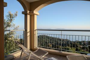 a balcony with chairs and a view of the mountains at Hôtel La Villa Douce in Rayol-Canadel-sur-Mer