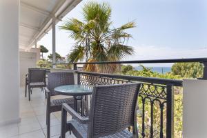 einen Balkon mit Stühlen, einem Tisch und einer Palme in der Unterkunft Bel Momento - Family Room in Alikanas