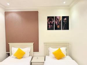 two beds with yellow pillows in a bedroom at توارن عنيزة in Riyadh +10 photos