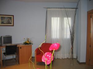 uma sala de estar com uma cadeira vermelha e uma secretária em Hotel SG em Bullas