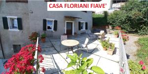 un patio con tavolo, sedie e fiori di Casa Floriani Fiavè-Comano Terme green a Fiavè