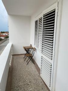 a small balcony with a table and shuttered window at Apartments Deli in Vrsi