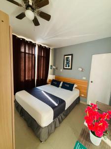 a bedroom with a bed with a ceiling fan and flowers at Ayenda Apart La Hacienda in Piura