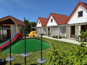 a yard with a playground with a slide at KORALIA Domki Standard z basenem in Sarbinowo