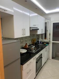 uma cozinha com armários brancos e uma pia em Hay el mohamadi agadir em Agadir mais 3 fotografias
