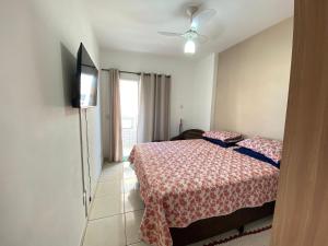 ein Schlafzimmer mit einem Bett und einem Flachbildfernseher in der Unterkunft Conforto na Praia – Apto 2 Qtos Guilhermina in Praia Grande + 17 Fotos