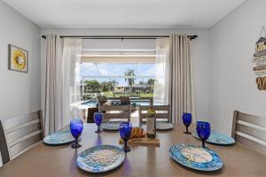 una mesa de comedor con platos azules y copas de vino en Charming Retreat with Paddleboards for Adventure - Much Ado About Sunshine - Roelens, en Cabo Coral