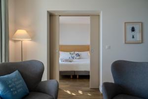 a bedroom with a bed and two chairs and a mirror at Hôtel La Villa Douce in Rayol-Canadel-sur-Mer