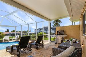 un patio con piscina, sillas y chimenea en Charming Retreat with Paddleboards for Adventure - Much Ado About Sunshine - Roelens, en Cabo Coral