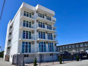 a white building with a fence in front of it at Milos Hotel in Zatoka