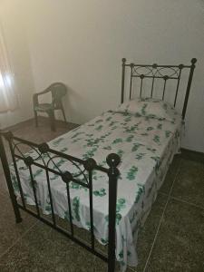 a bed with a green and white comforter and a chair at Praise Health Services in Valencia Village