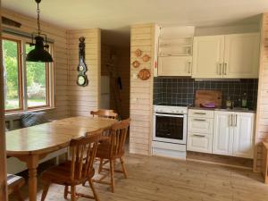 eine Küche mit Holztisch und eine Küche mit weißen Schränken in der Unterkunft Alljungen in Holmsjö