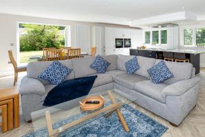 a living room with a gray couch with blue pillows at NEW! Stunning & Modern 5 bedroom home with Parking & Garden - Excellent Location! in Saint Leonards