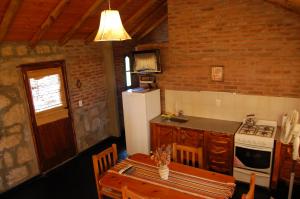 a kitchen with a table and a white refrigerator at Alto Valle Cabañas de Montaña in Mina Clavero