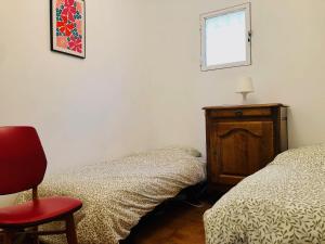 a bedroom with two beds and a red chair at Villa Le Pin in Rognes +9 photos