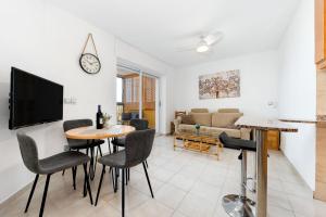 a living room with a table and chairs and a tv at Apartament z widokiem na morze 250 m od plaży in Torrevieja