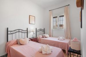 1 Schlafzimmer mit 2 Betten mit rosa Bettwäsche und einem Spiegel in der Unterkunft La Solana in Chiclana de la Frontera + 21 Fotos