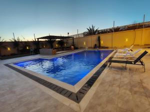 a swimming pool with two chairs sitting next to a building at Janna2Villa in Tall al Misţāḩ