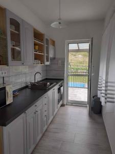 a kitchen with white cabinets and a sink and a door at Holiday home in Balatongyörök 42286 in Balatongyörök