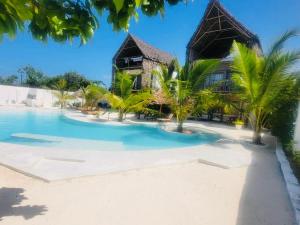 a resort with a swimming pool in front of a building at Mfumbwi Twins Apartments in Jambiani
