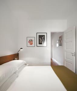 a white bedroom with a large white bed and pictures on the wall at Flattered to be in Tomar in Tomar