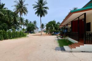 un camino de tierra junto a un edificio con palmeras en First Light beach bungalow 1, en Ko Pha Ngan