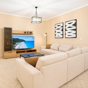 a living room with a white couch and a flat screen tv at Elena’s House Sivota Lefkadas in Sivota