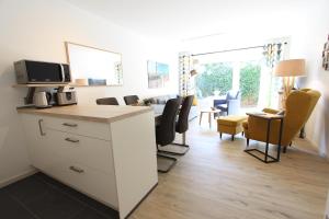 a living room with a kitchen and a living room with chairs at Strandliebe in Langeoog +8 photos