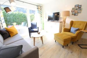 a living room with a couch and two chairs and a tv at Strandliebe in Langeoog