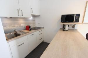 a kitchen with white cabinets and a sink and a microwave at Strandliebe in Langeoog