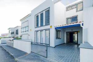 ein weißes Wohnhaus mit einer Tür und einem Bürgersteig in der Unterkunft Casa de Julho - Beach House in Livramento