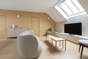 a living room with a couch and a tv at Le Refuge des Clavendiers in Nuits-Saint-Georges