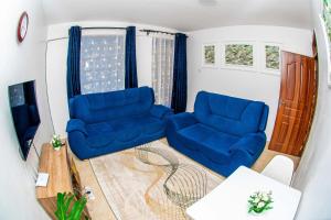 ein Wohnzimmer mit zwei blauen Sesseln und einem Tisch in der Unterkunft Hamptons Homes Stylish 1 Bedroom Stay close to Eldoret Town in Eldoret