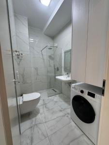 ティラナにあるTirana Center Boulevard Apartmentの白いバスルーム(シャワー、洗濯機付)