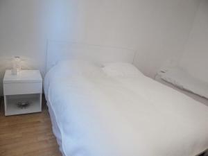 a bedroom with a white bed and a night stand at Small Hill Apartments in Sarajevo