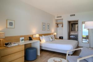 a bedroom with a bed and a desk and a chair at Hôtel La Villa Douce in Rayol-Canadel-sur-Mer