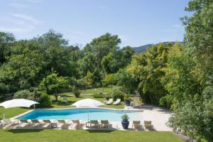 una imagen de una piscina con sillas y árboles en Hotel Le Verger Maelvi en Grimaud
