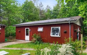 a red shed with a white door at Three Bedroom Cozy Home In Ebeltoft in Ebeltoft +2 photos