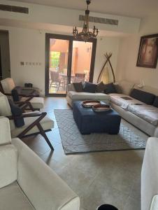 ein Wohnzimmer mit Sofas und einem blauen Ottomanen in der Unterkunft Town House in Veneto Residence Marassi in El-Alamein