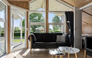 a living room with a black couch and large windows at Pet Friendly Home In Hejls With Sauna - F04167 in Hejls