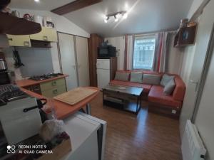 a small living room with a couch and a kitchen at Mobilhome 4-6 personnes confort-piscine-mer meschers sur gironde in Meschers-sur-Gironde