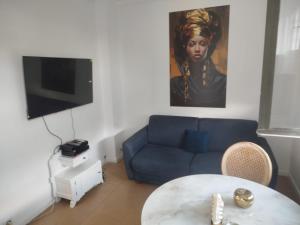 a living room with a blue couch and a table at Résidence P&C Fragrance Studio in Neuilly-sur-Marne