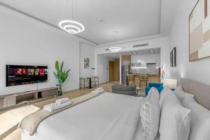 a bedroom with a large white bed and a living room at Modern Studio In Jlt Cluster L Top Facilities in Dubai