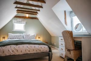 ein Schlafzimmer mit einem Bett und einem Stuhl auf einem Dachboden in der Unterkunft Abbey Gate Cottage, Faversham Near to Whitstable in Kent