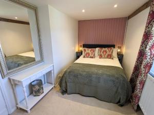 ein Schlafzimmer mit einem großen Bett und einem Spiegel in der Unterkunft Abbey Gate Cottage, Faversham Near to Whitstable in Kent