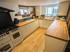 eine Küche mit weißen Schränken und einer Holzarbeitsplatte in der Unterkunft Abbey Gate Cottage, Faversham Near to Whitstable in Kent