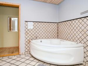 a white tub in a bathroom with a tiled wall at 9 person holiday home in Jægerspris-By Traum in Jægerspris