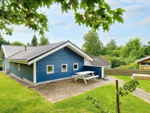 a blue house with a picnic table in the yard at 9 person holiday home in Jægerspris-By Traum in Jægerspris