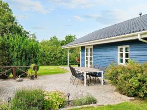 a patio with a table and chairs in front of a blue house at 9 person holiday home in Jægerspris-By Traum in Jægerspris